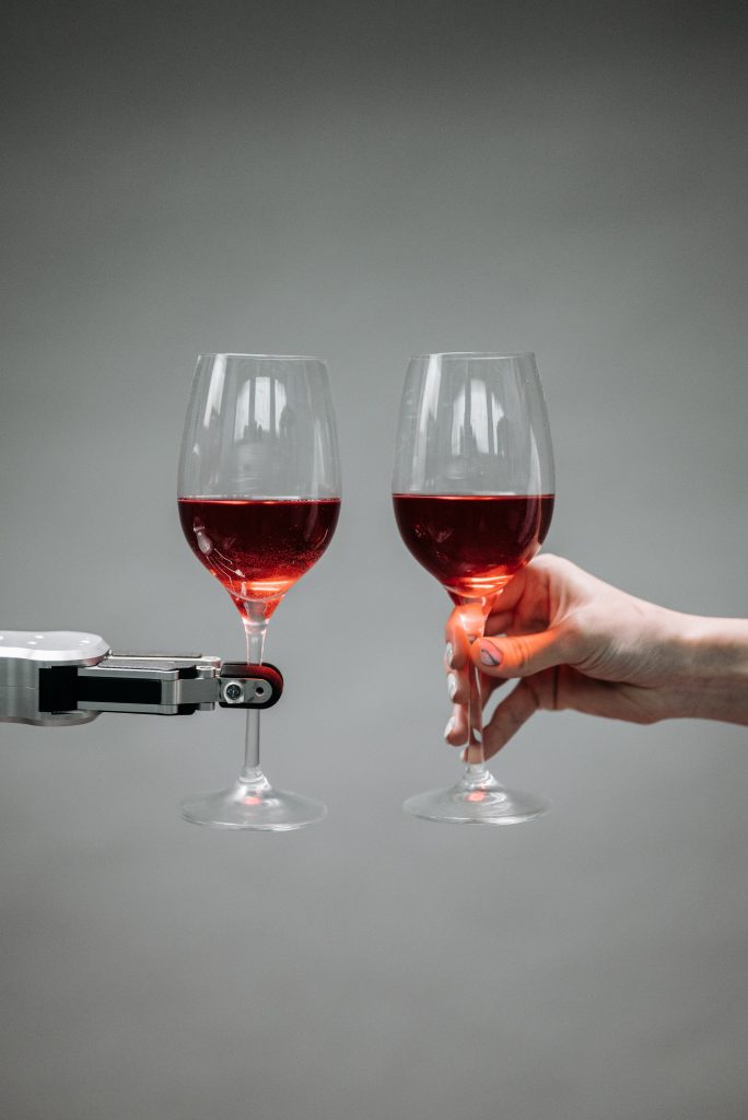 a man and a robotic arm holding a wine glass