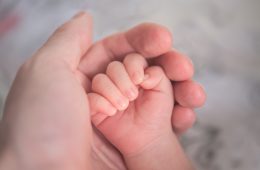A parent holding a baby's hand