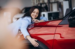A women hugging her new red car
